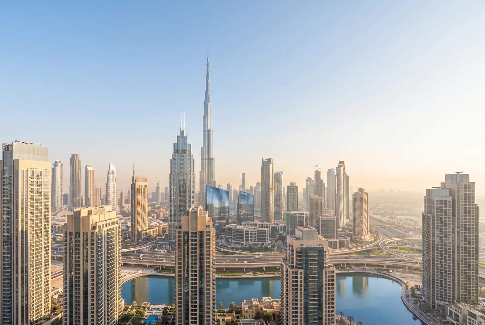 The Dubai skyline in clear daytime light, the Burj Khalifa rising above the downtown towers and waterway